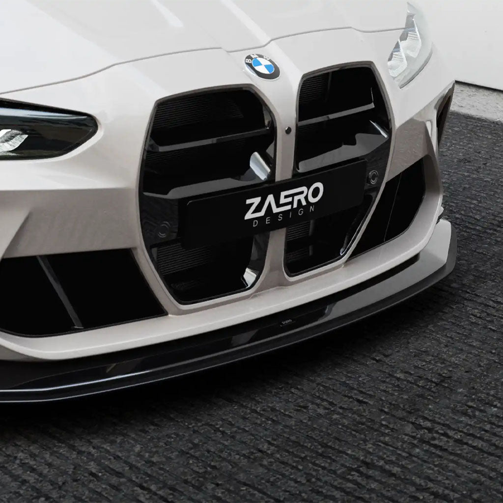 Nahaufnahme eines ZAERO Design EVO-S Frontgrill passend für BMW M3 G80, G81, M4 G82, G83 von ZAERO, dargestellt mit einem Nummernschild auf einer strukturierten schwarzen Oberfläche.