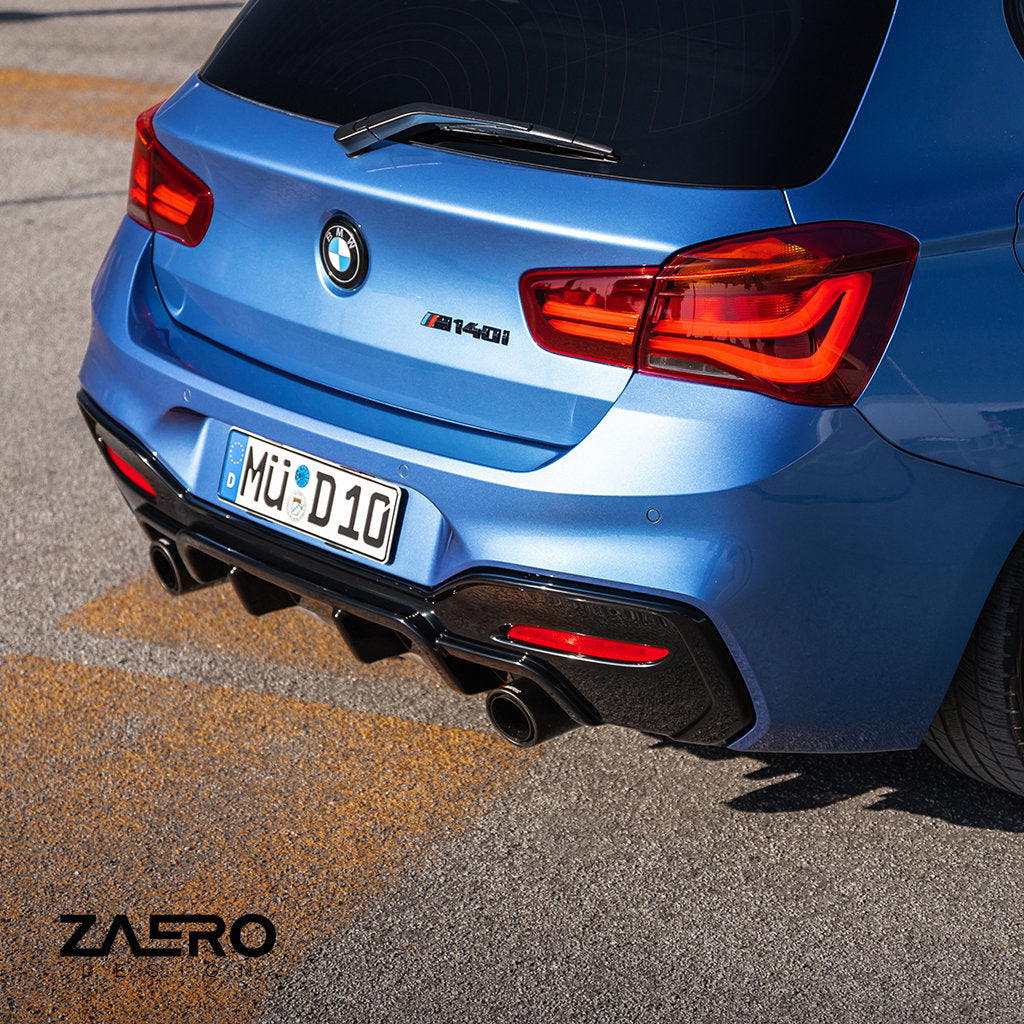 Rückansicht eines blauen BMW M140i F2x mit glänzend schwarzen Carbon-Anbauteilen und einem sportlichen ZAERO Evo-1 Diffusor von ZAERO mit Doppelauspuff, geparkt auf Asphalt.