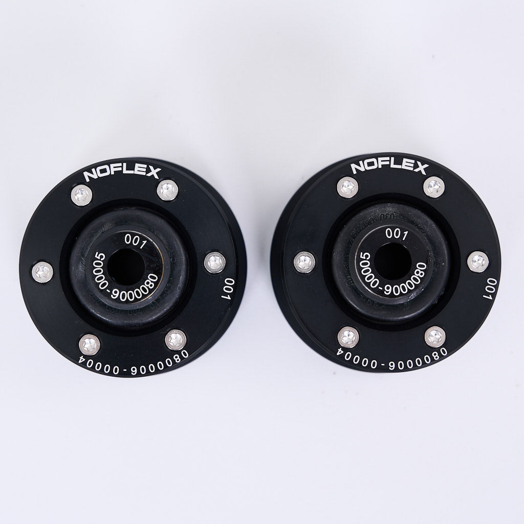 Zwei schwarze runde NoFlex Lager (Uniball Lager vordere Zugstrebe) von 55Parts mit silbernen Schrauben sind auf weißem Hintergrund abgebildet, ideal für BMW 3er E90-E93 xDrive oder X1 E84 xDrive Liebhaber, die sich für Fahrwerksmodifikationen interessieren.