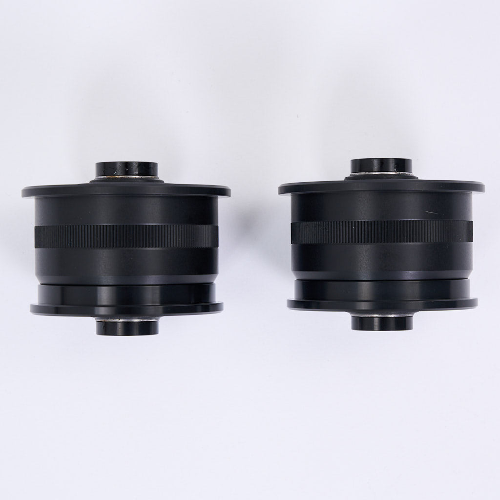Zwei schwarze zylindrische NoFlex-Lager (Uniball Lager, 55Parts) für BMW 3er E90/E91/E92/E93 xDrive und X1 E84 xDrive sind nebeneinander auf weißem Grund angeordnet.