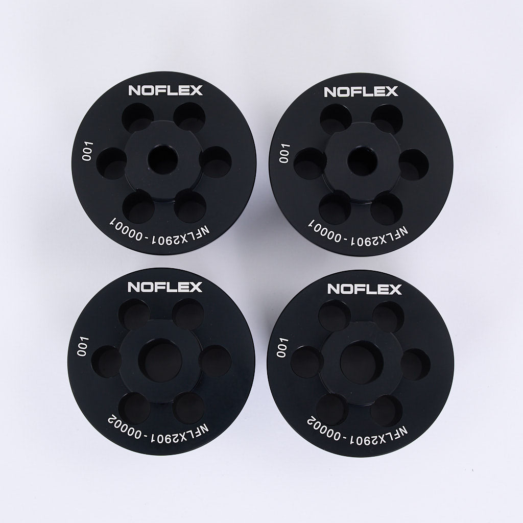 Vier schwarze zylindrische NoFlex Aluminium Tonnenlager von 55Parts, jeweils mit eingeätzten Teilenummern, als Hinterachslager für BMW 3er E46, Z4 E85/E86/E89 und X3 E83, dargestellt auf einer weißen Fläche.