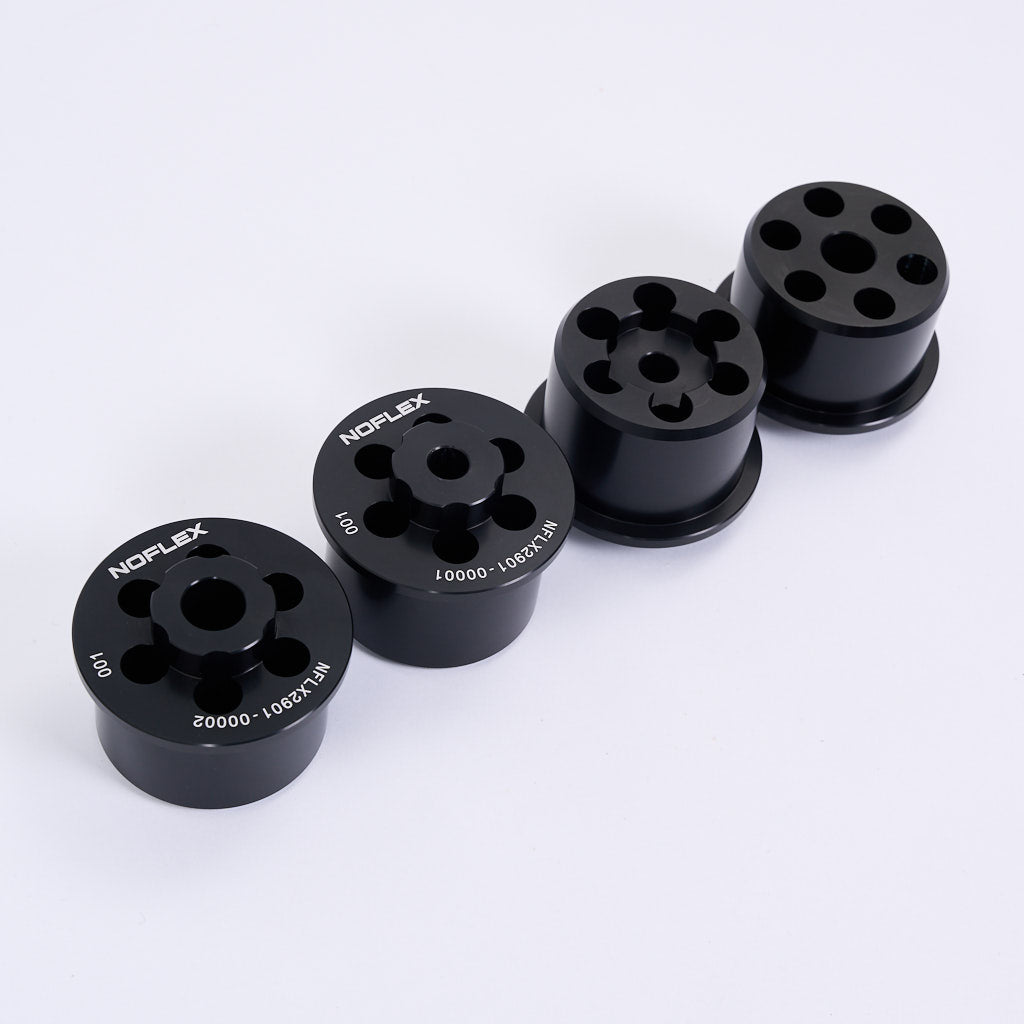 Vier schwarze NoFlex-Lager von 55Parts-Aluminium Tonnenlager Hinterachslager für BMW 3er E46, Z4 E85/E86/E89 &amp; X3 E83 sind in einer Reihe dargestellt, jeweils zylindrisch mit mehreren Löchern, auf weißem Hintergrund.