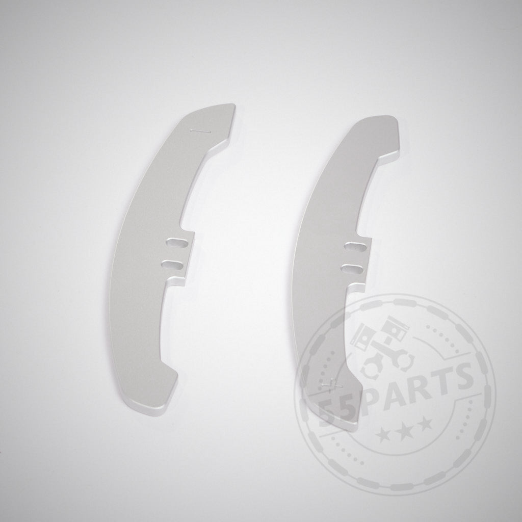 Zwei silberne, gebogene Metallteile mit zwei rechteckigen Aussparungen auf weißem Untergrund – 55Parts Special: CNC gefräste Aluminium Paddles für Magnetische Schaltwippen / magnetic paddle Shifter.