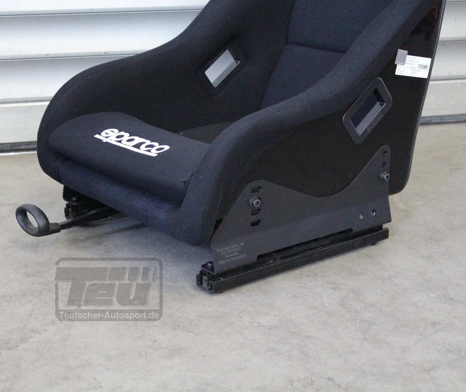 Zwei schwarze Metallkonsolen mit Schrauben und Unterlegscheiben, dargestellt auf hellem Hintergrund mit dem TEU-Logo. Teutsche Recaro, Sparco, OMP Sitzkonsolen passend für Mini R50 R53 incl. Materialnachweis.