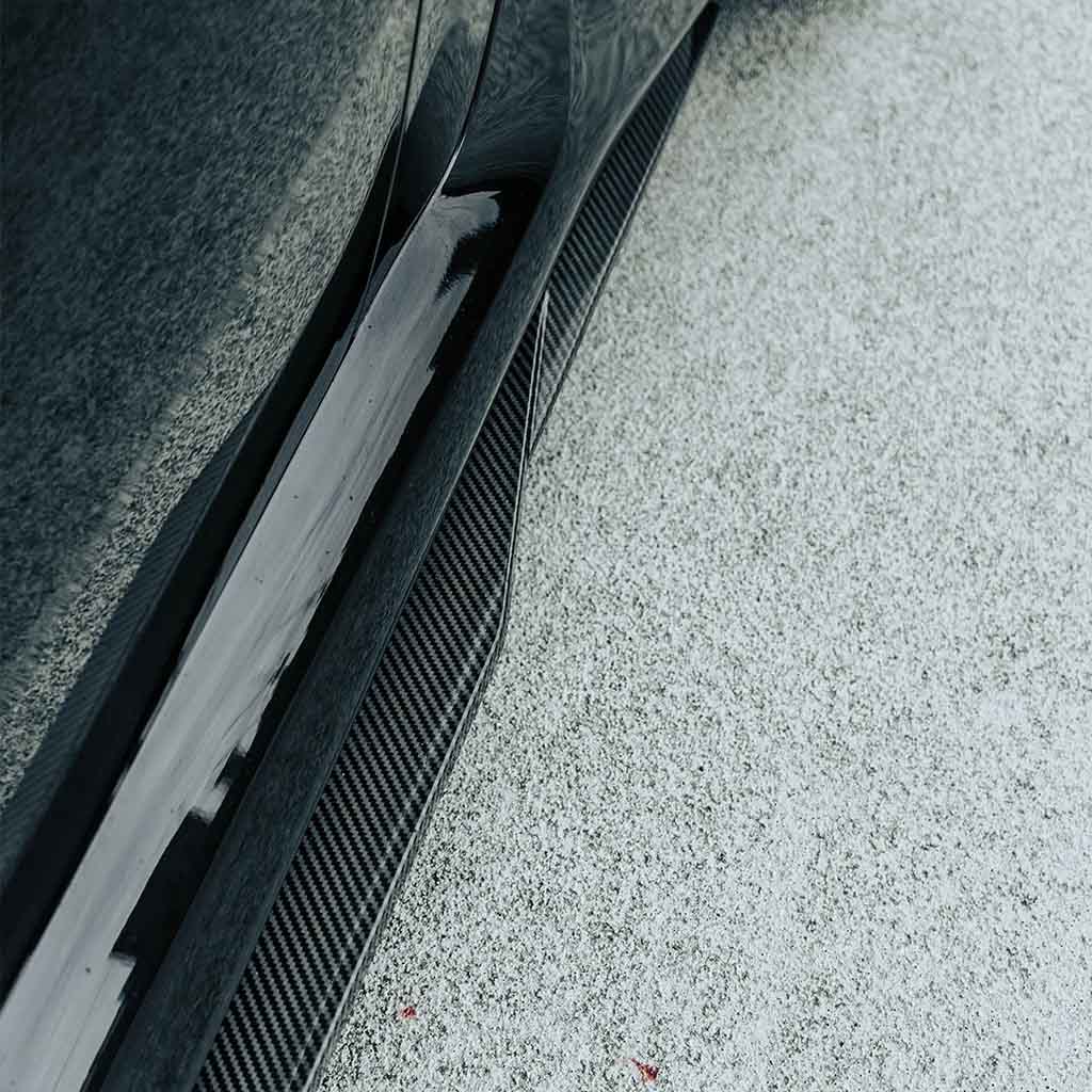 Nahaufnahme einer Twistnfix MHC TNF+ Edition 1 Seitenschweller Carbon Seitenschweller für BMW M2 (G87) inkl. Teilgutachten. Teilgutachten, dargestellt auf hellem, strukturiertem Grund.