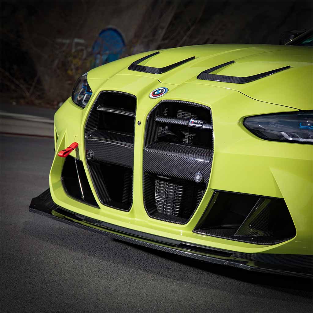 Nahaufnahme eines gelben BMW mit Twistnfix TNF+ V-Style Carbon Frontgrill, passend für BMW M3 (G80/G81) &amp; M4 (G82/G83), inkl. Teilegutachten, mit Details aus Carbonfaser.