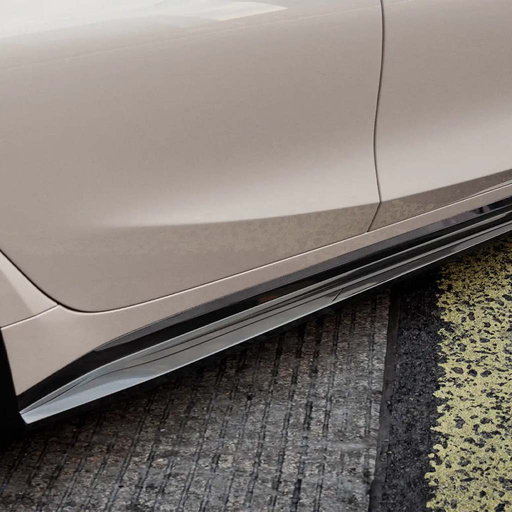 Nahaufnahme eines eleganten, beigen BMW M3 G80 mit ZAERO Design EVO-S Seitenschweller, geparkt neben einem strukturierten gelb-schwarzen Bordstein.