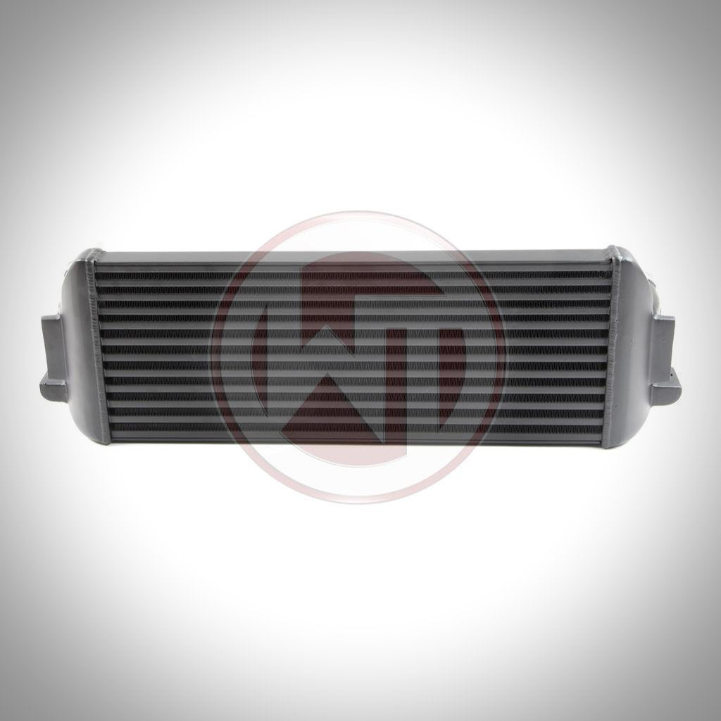 Der Wagner Tuning Evo 1 Competition Ladeluftkühler passend für BMW F2x, F3x in Schwarz und Silber mit seitlichen Einlass- und Auslassrohren ist ideal für einen FBO-Aufbau, abgebildet auf weißem Hintergrund.