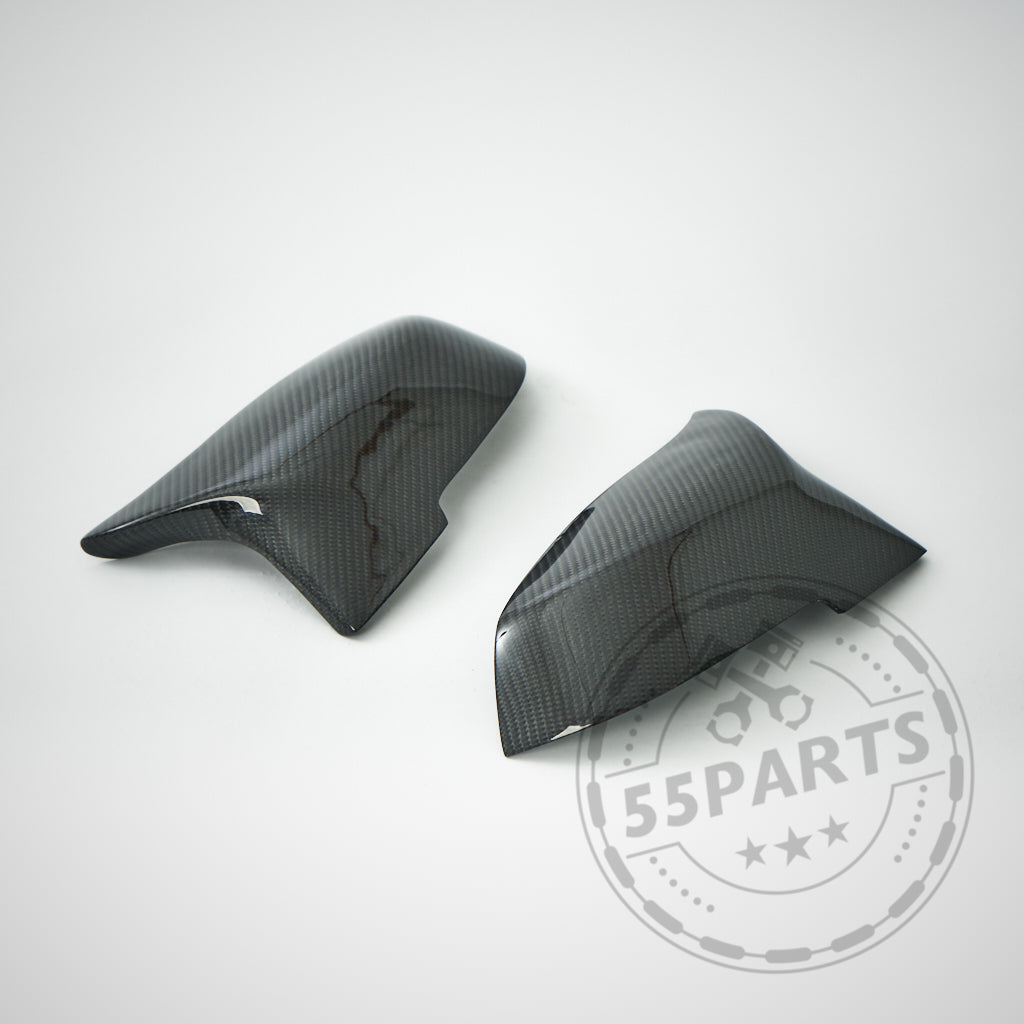 Zwei schwarze 55Parts Spiegelkappen, entworfen passend für BMW F87 F2x F3x M2 M135i M140i M340i, ruhen auf einer hellen Oberfläche mit einem schwachen 55Parts-Logo-Wasserzeichen und zeigen ihren hochwertigen Carbon-Stil und ihr elegantes Aussehen.