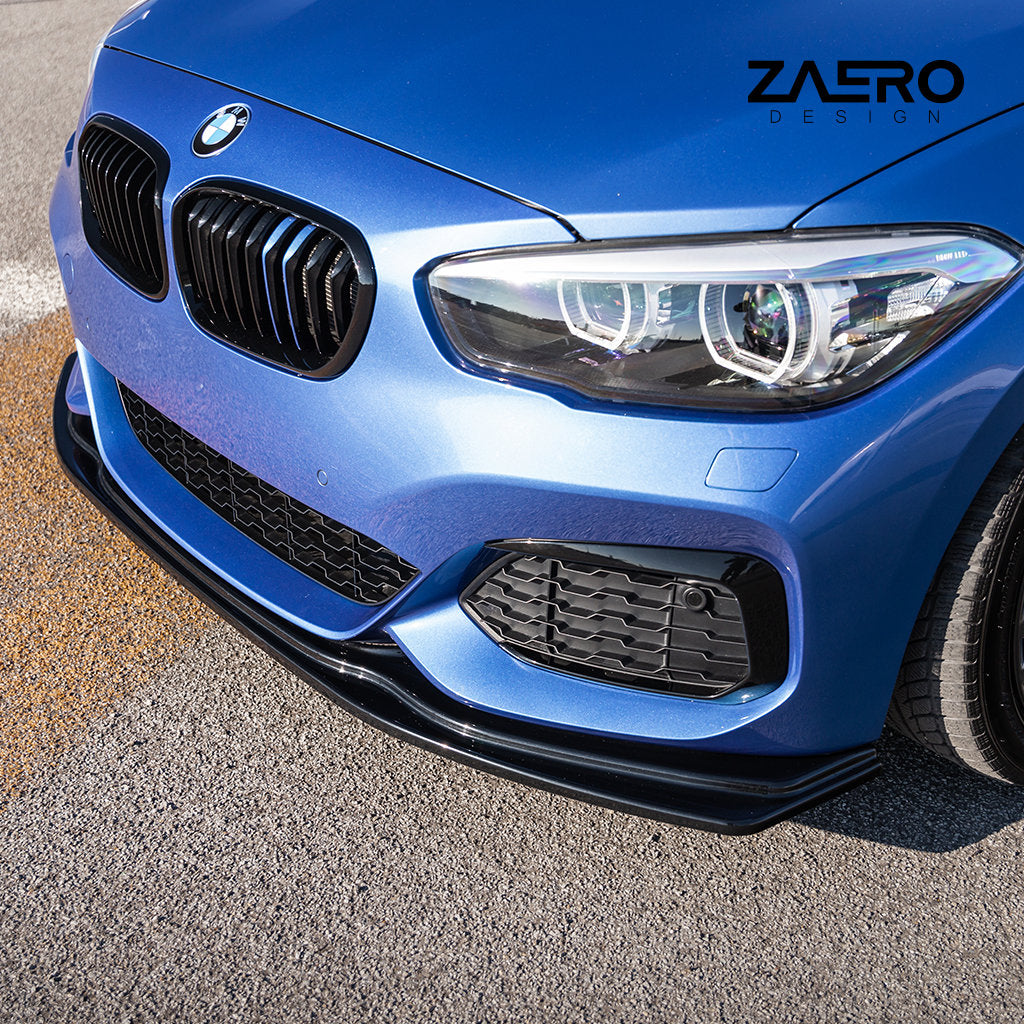 Nahaufnahme eines blauen BMW F2x mit einem ZAERO Evo-1-Frontspoiler in Hochglanzschwarz, der die Frontstoßstange und den Scheinwerfer auf einer grauen Asphaltoberfläche zur Geltung bringt.